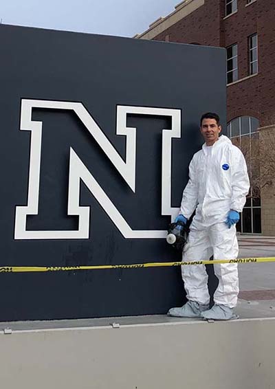 Man stands on a cement block with the University of Nevada, Reno N logo sign.
