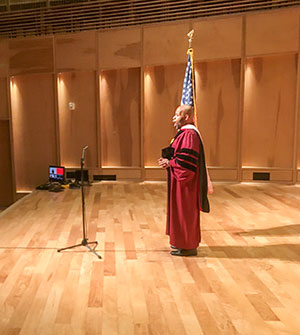 Albert Lee wears graduation regalia and sings on stage