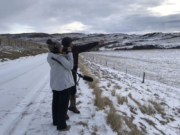 Tsanavi Spoonhunter stands with another filmmaker in a snowy mountain landscape.