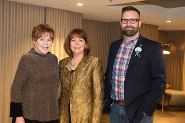 Three people standing together posing for a group photo. Photo, from left to right, is of the 2019 Nevada Writers Hall of Fame honorees Robyn Carr and Caleb S. Cage with University Libraries Dean Kathlin Ray.