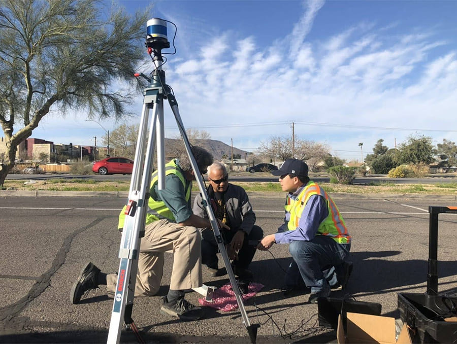 Three workers setting up a roadside LiDAR sensor