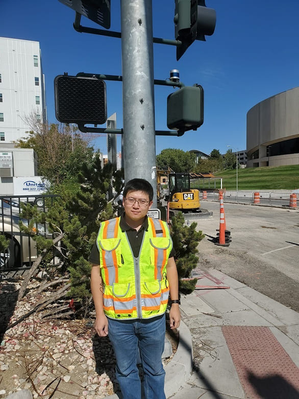 person in construction gear standing in front of streetlight with LiDAR sensor