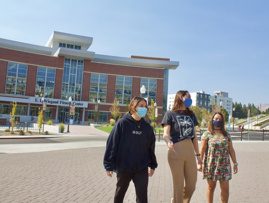 Students wearing face masks walking in front of the fitness center