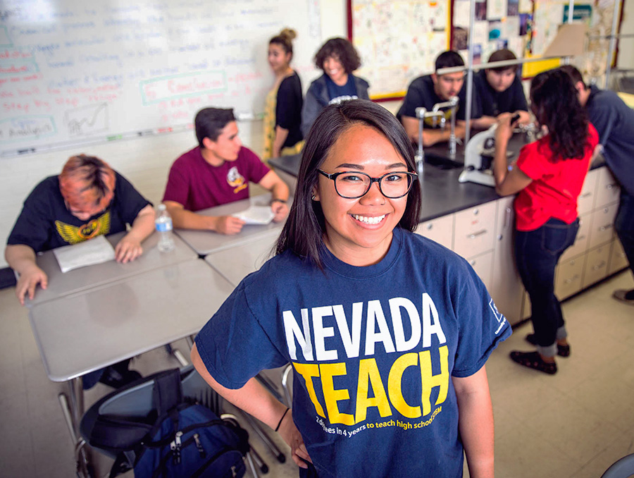 Nevada Teach student smiling with students in the background working on science project