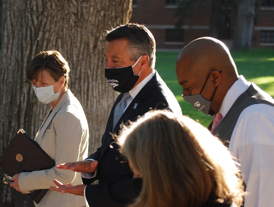 President Sandoval talks with senior administrators while walking on the quad