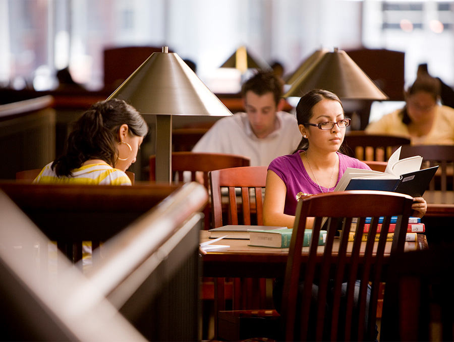 Students sitting at the study tables in the Mathewson-IGT Knowledge Center, studying and looking through books.