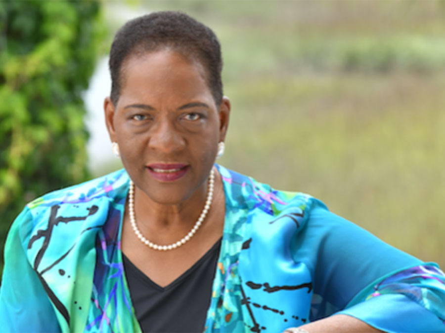 Wanda Lloyd smiles to camera in front of a grassy backdrop. 