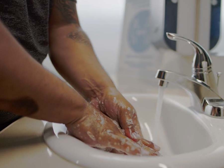 A person washes their hands in a sink with soap.