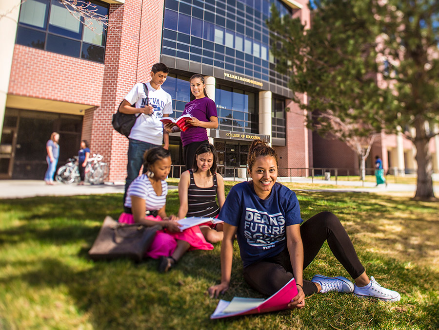 Student wearing Deans Future Scholars shirt in front of the College of Education in the summer