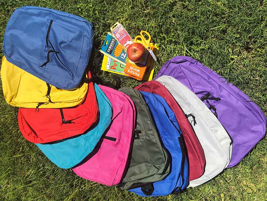 Backpacks of different colors with school supplies 