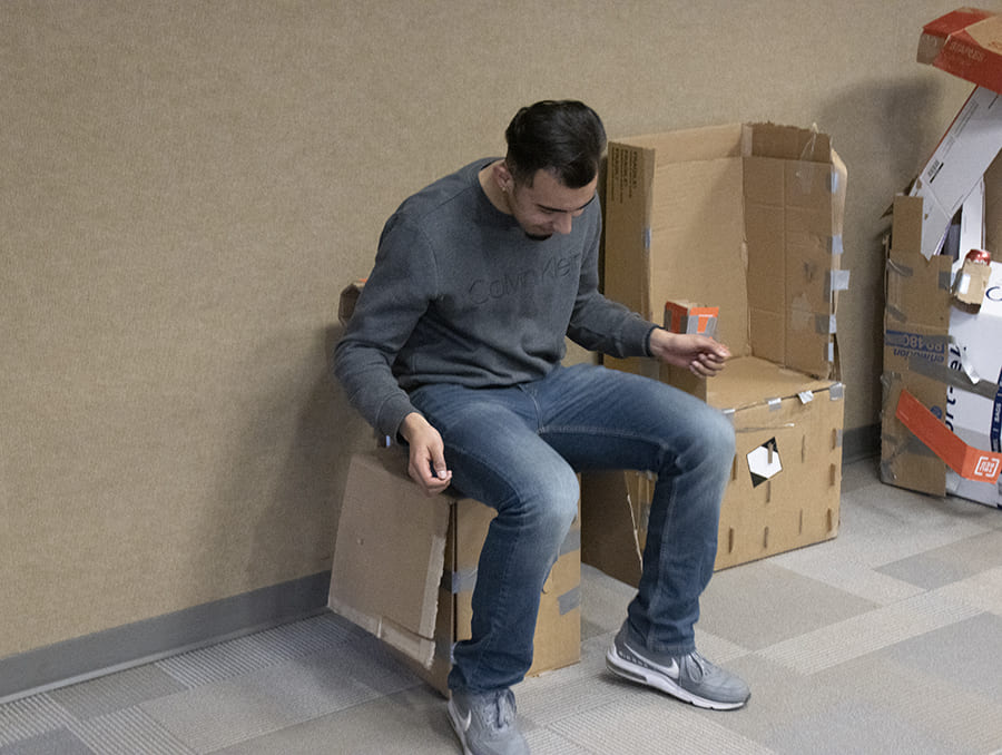 student sitting on cardboard chair