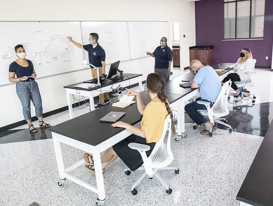 students and teachers in classroom with writing on white board