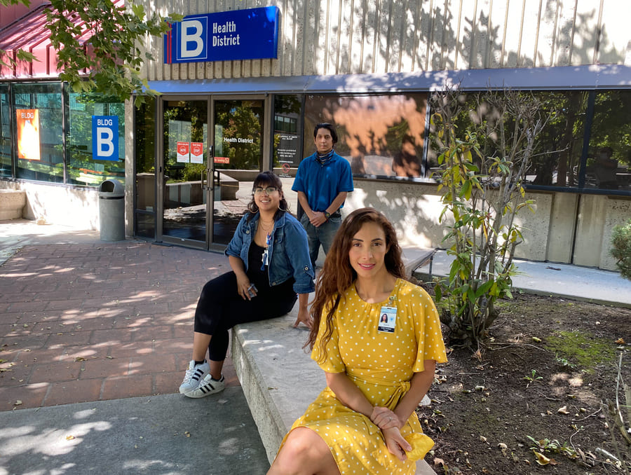 Nevada Public Health Training Center disease investigators Dulce Leyva, Cynthia Cabrales, seated, and Luis Godoy, standing, in a shaded courtyard at the Washoe County District Health facility in Reno.