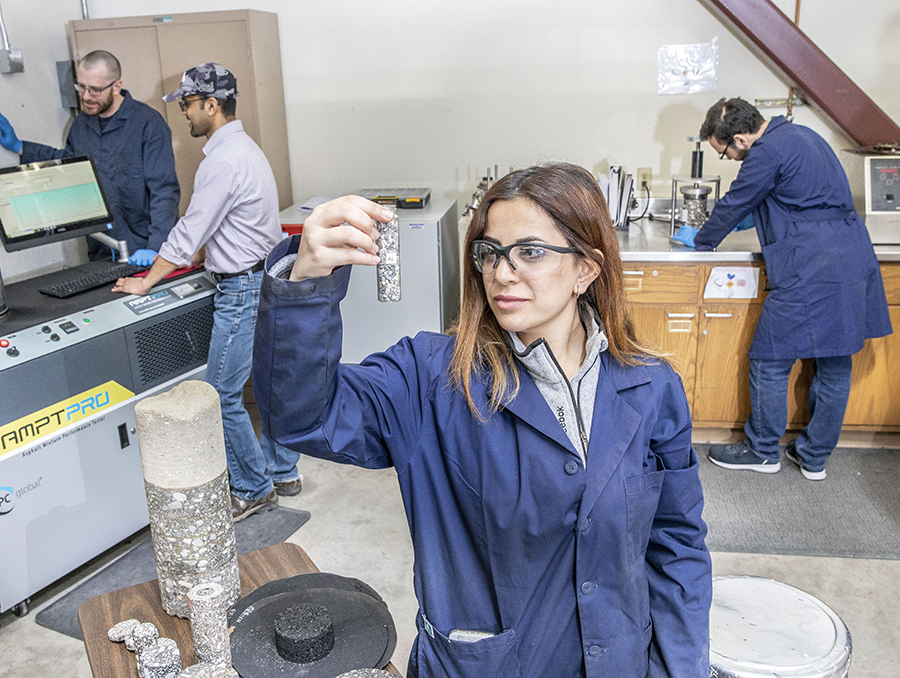 Nicole Elias in pavements lab, holding vial of road samples