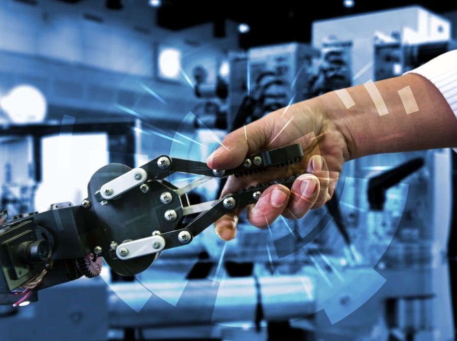 A robotic arm shakes hands with a human hand