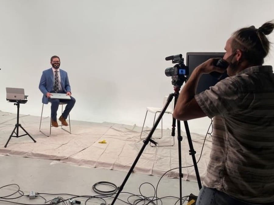 Tim Robb sits in a studio being filmed for an interview. 