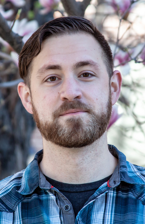 Photo of man with beard wearing a blue and black plaid shirt