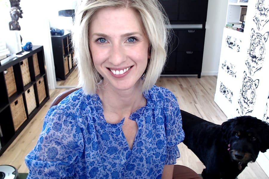 Woman smiles in a home office with dog. 