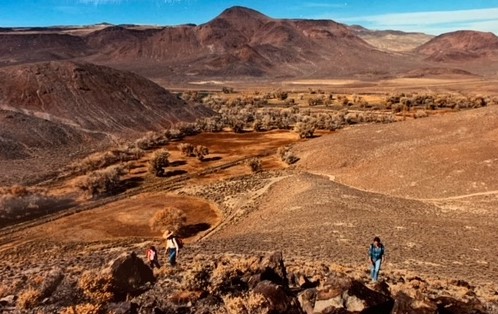 Three hikers climbing the side of a mountain