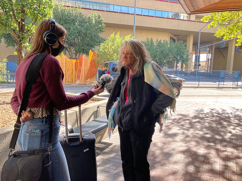 A student interviews a woman who is experiencing houselessness.