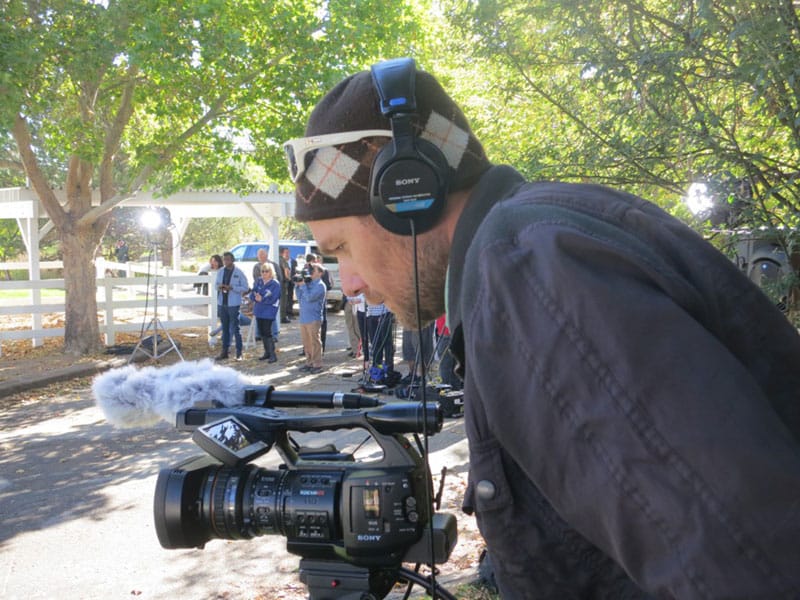 Nico Colombant stands behind a video camera outdoors.