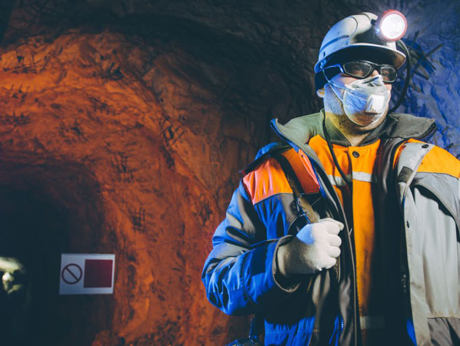 Man in an underground mine wears a face covering.