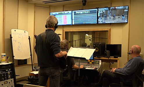 Three people in a recording studio working on project