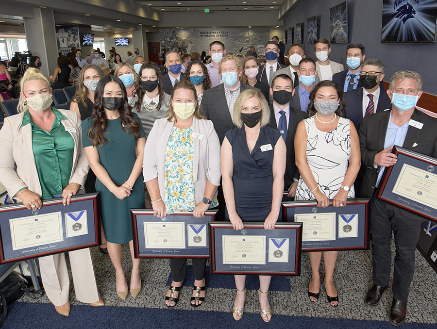 The 2021 Online Executive MBA graduating class posing for a group photo while holding their degrees.