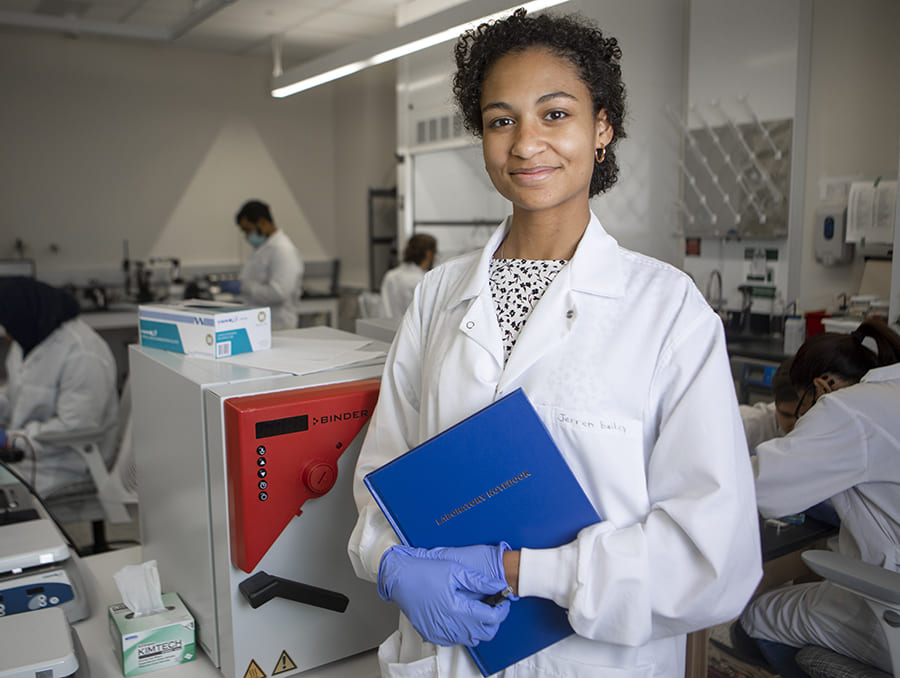 Jerren Bailey in lab coat standing in front of busy laboratory