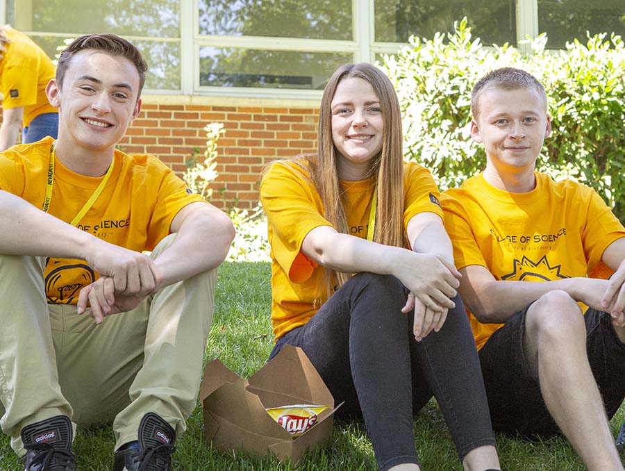 Students sit on a grass hill with yellow shirts during an event on the University of Nevada, Reno campus.