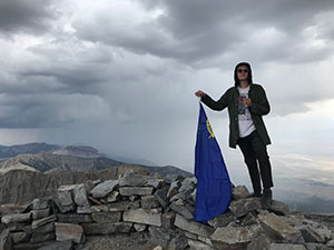 Austin Pratt holds flag at the top of Wheeler Peak