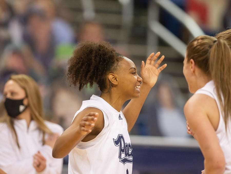 Nevada Wolf Pack Women's Basketball players celebrating on the court with a crowd visible in the background