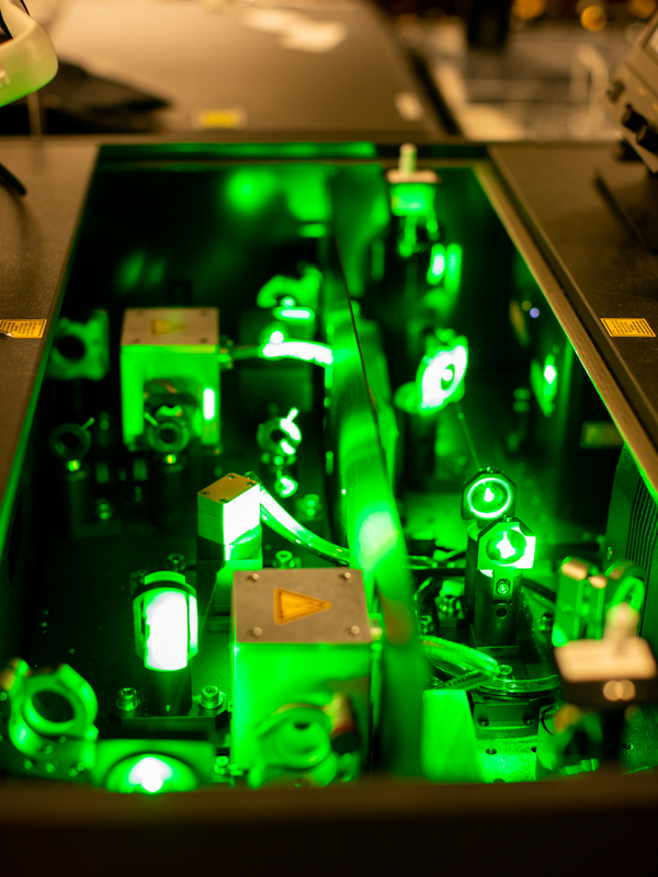 A green laser beam bounces off the mirrors of a rectangular device.