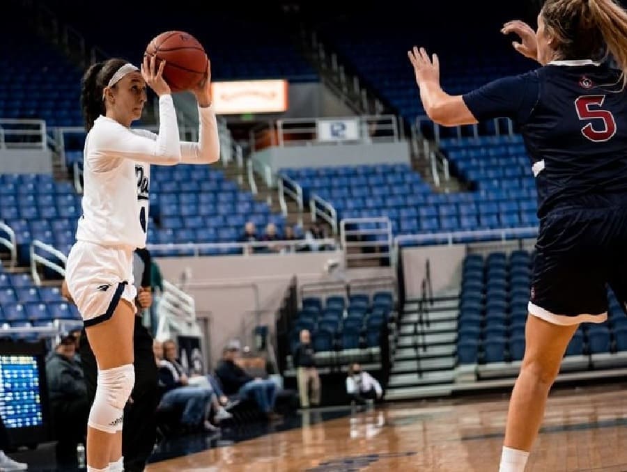 Audrey Roden about to take a shot during a basketball game with an opposing team member attempting to block