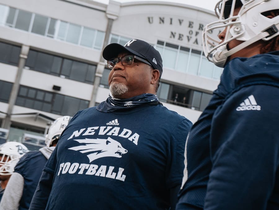 Dean Coach Don Easton-Brooks with football players in Mackay Stadium looking into the distance