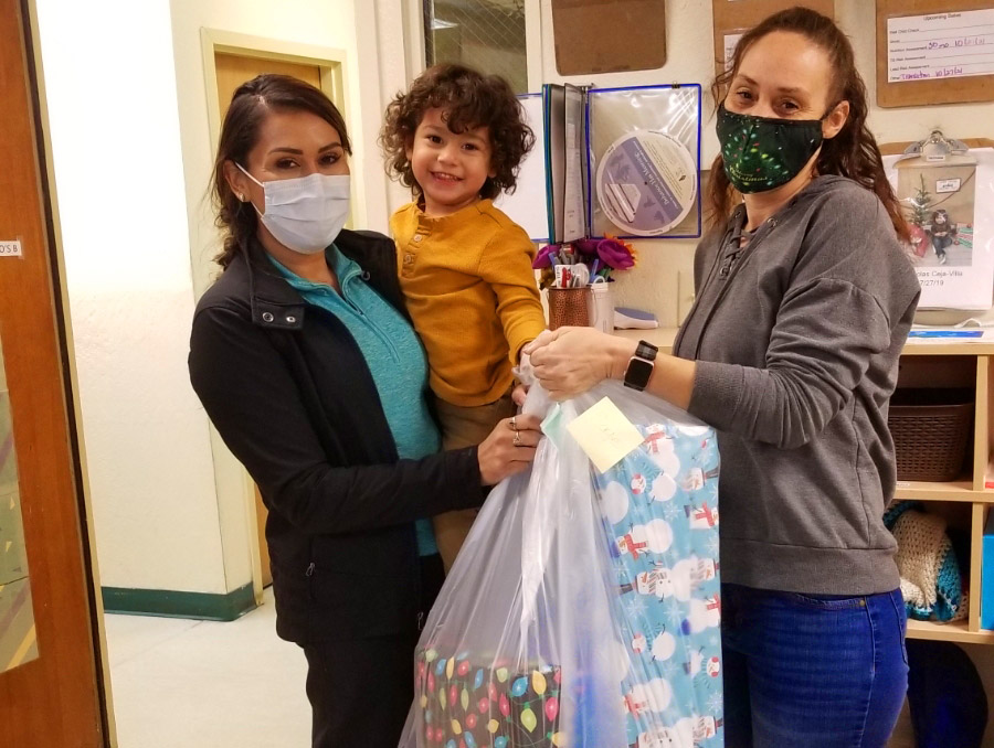 Child and mother receiving wrapped presents from staff