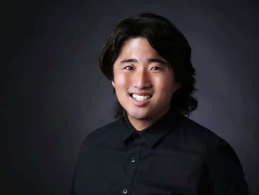 Lukas Eggen smiles to camera in front of a black background.