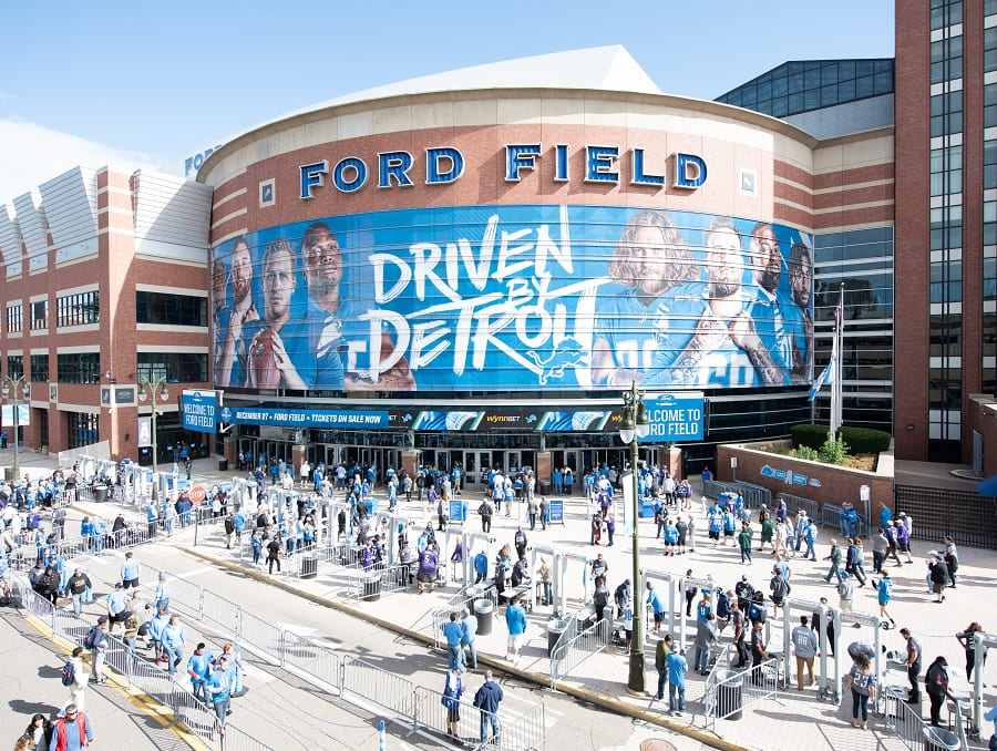 Ford Field stadium exterior in Detroit with large advertisement for the 2021 Quick Lane Bowl