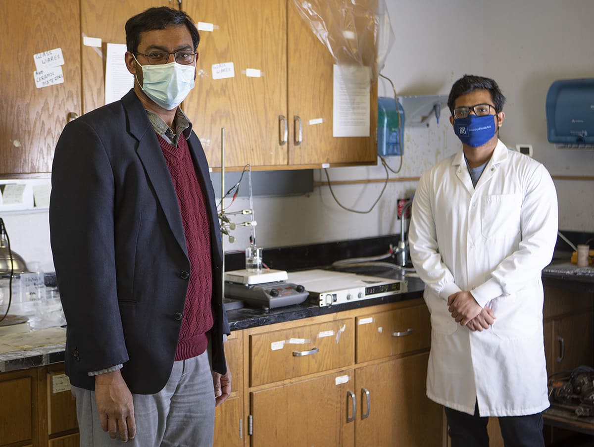 Two people in lab near equipment used for disinfectant