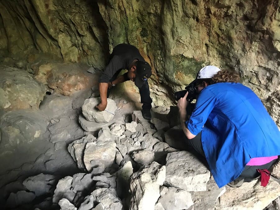 Caitlin Earley photographing a Maya sculpture in a cave.