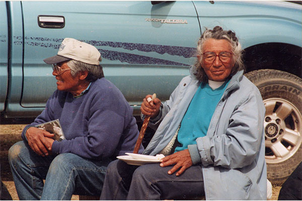 two women (sisters) sitting in lawn chairs in front of a light blue Toyota Tacoma truck