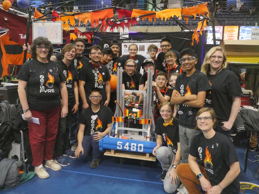 Kerry Thompson and her team of students stand around the robot they built at a competition.