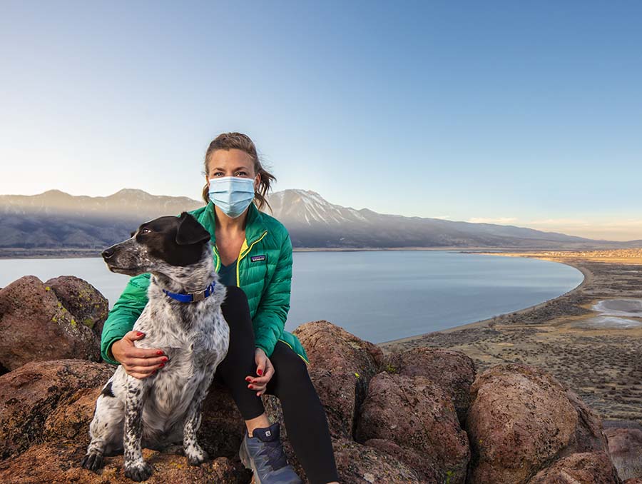 Assistant professor Kyra Stull with her dog Ozymandias sitting on rocks overlooking Washoe Valley Lake