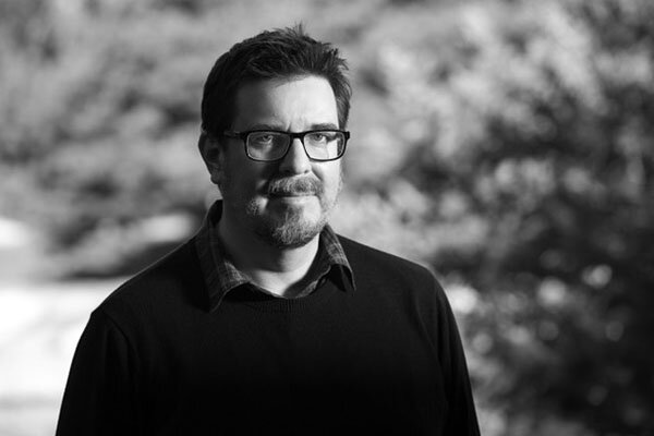 Black and white image of a man wear glasses and posing.