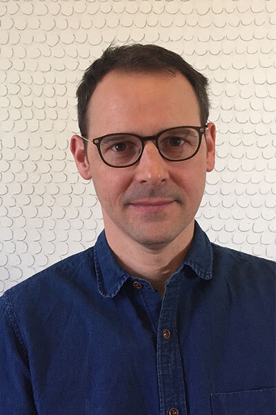 Portrait of a man with black glasses and wearing a blue button-up