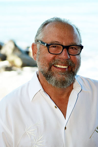 Portrait of an older man with facial hair and black glasses, posing.