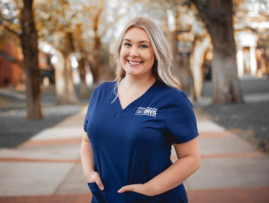 University of Nevada, Reno alumna Mariah Zinn poses for a photo in her nursing scrubs near the University of Nevada, Reno Quad.