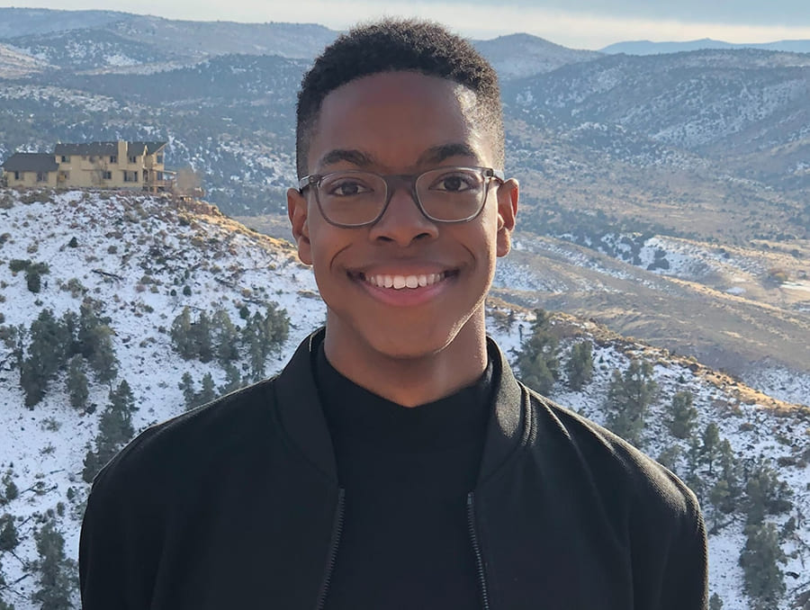 Tyreis Gatson with snow-capped mountains and valleys behind him