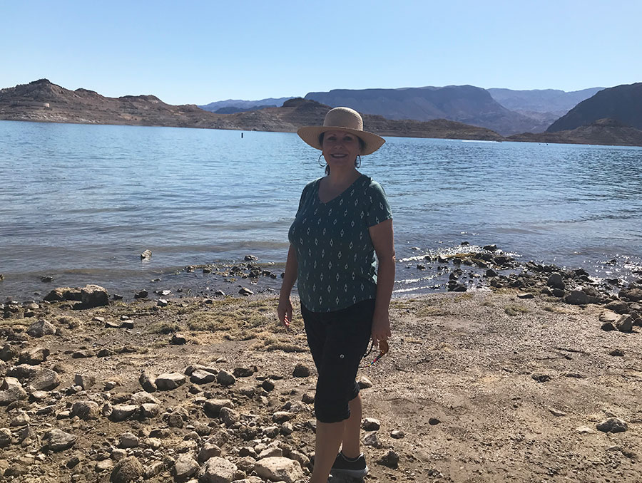 Eugenia Weiss standing by a lake wearing a green shirt, black leggings and a hat