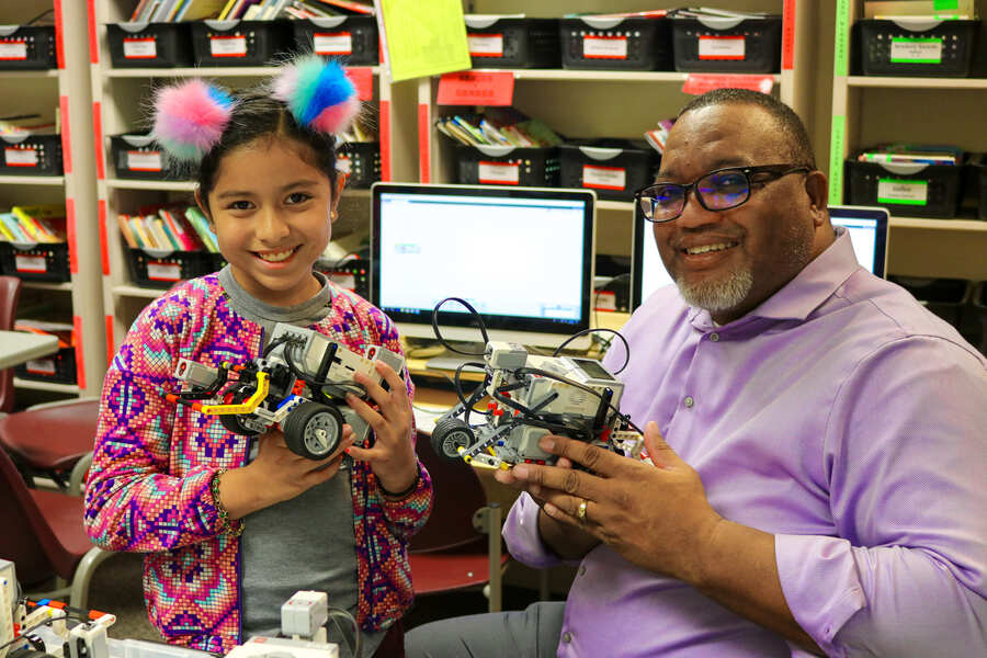Donald Easton-Brooks and student pose for photo holding robots
